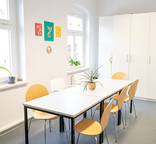 Der Kreativraum mit einem langen Tisch mit Stühlen und einem Schrank im Hintergrund bei der Ergotherapie Meyer in Ottendorf Okrilla